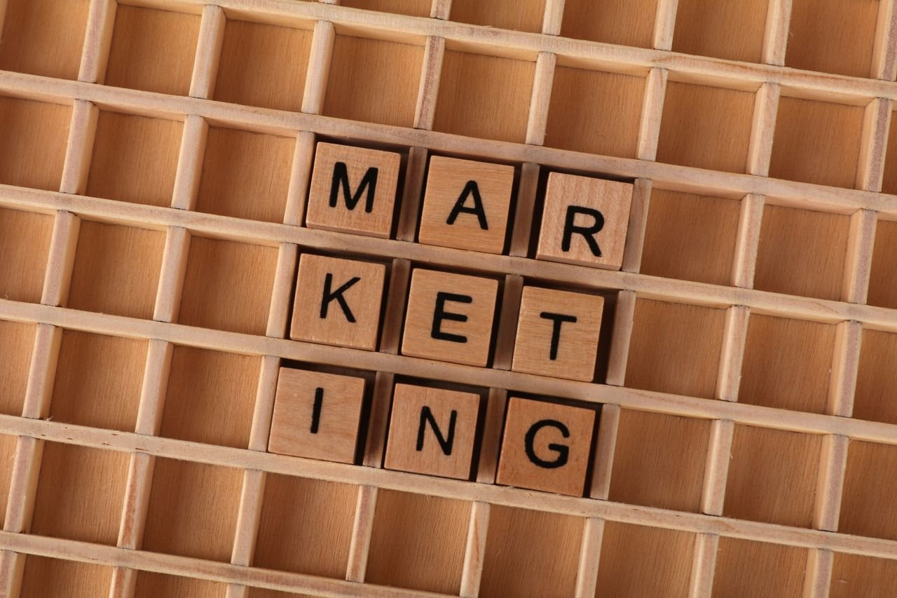 Wooden letter tiles spell out the word marketing on a grid background, showcasing creativity and business concept.